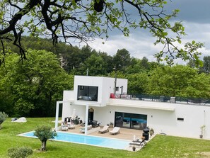 Une maison moderne dotée d’une piscine, d’un espace salon extérieur et d’un garage.