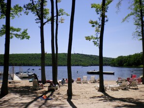 A beach with several lounge chairs and a small dock area with boats.