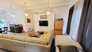 Ein Wohnzimmer mit einer Couch, einem kleinen Tisch, einem Fernseher und einem Schrank.