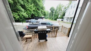 Eine Terrasse mit Grill, Holzbank und Fußmatte.