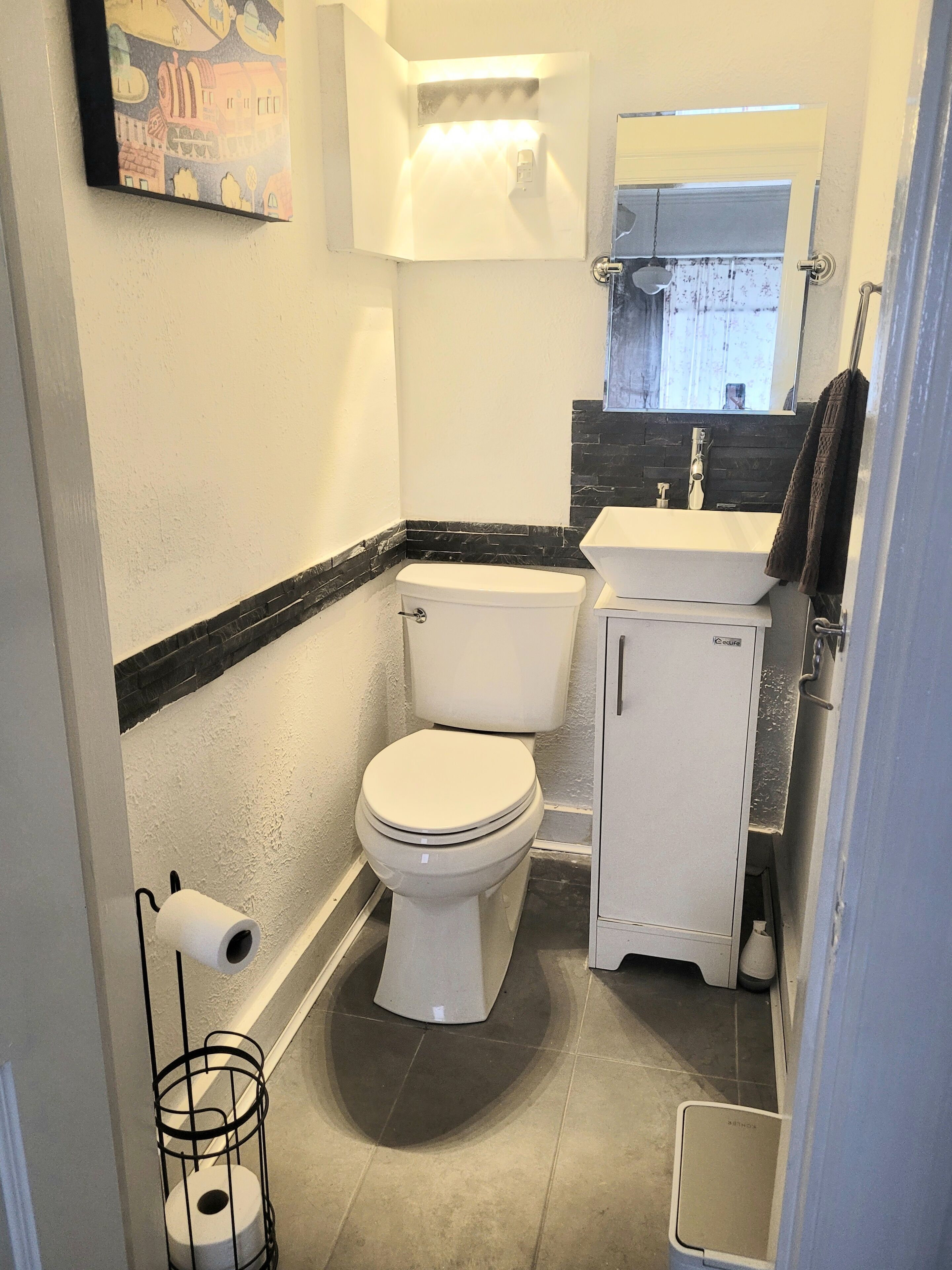 A compact bathroom with a toilet, sink, and a small cabinet.