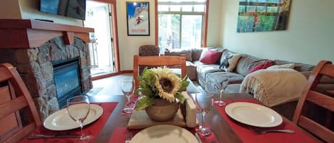 A dining area with a stone fireplace, a sofa, and a painting on the wall.