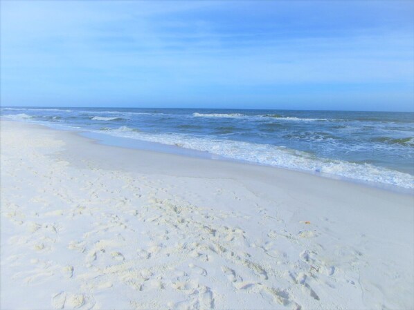 Una playa con arena blanca y olas del océano.