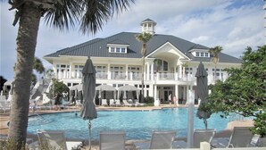 Un resort con una piscina grande, sillas de descanso y un edificio de dos pisos con balcones.