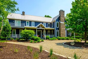 A two-story house with a front porch, a stone chimney, and a well-maintained garden. - 7 Bedroom Country Estate with Large Private Pool! (Sawyer)