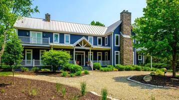 A two-story house with a front porch, a stone chimney, and a well-maintained garden.