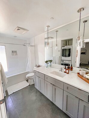 Une salle de bain moderne avec un grand miroir, des toilettes, une douche et un lavabo.