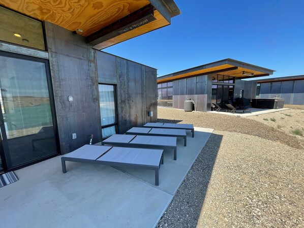 Un edificio moderno con fachada de hormigón, amplias ventanas y un patio con mobiliario.