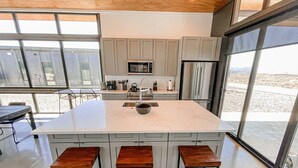 Una cocina moderna con una isla grande, electrodomésticos de acero inoxidable y vista a la playa.