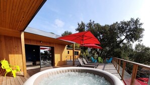 A hot tub on a wooden deck with lounge chairs and umbrellas. - Villa Le Repère, quiet area, air-conditioned with swimming pool (SAINT AYGULF)