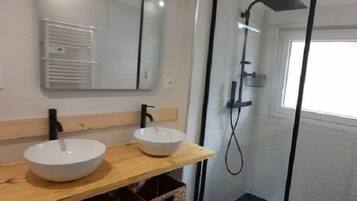 Ein Badezimmer mit zwei Waschbecken, einem Spiegel und einer Dusche.