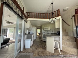 Una cocina amplia con una isla central, un comedor con techo alto de madera y vistas al exterior.