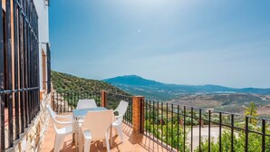 Une terrasse avec une table et des chaises, offrant une vue sur un paysage montagneux.