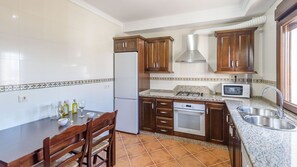 A kitchen with wooden cabinets, a white refrigerator, a stove, a microwave, and a sink. - Finca Cerro Alcolea Periana by Ruralidays (Málaga)