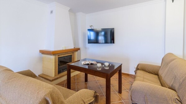 A living room with a fireplace, a TV mounted on the wall, and two sofas. - Finca Cerro Alcolea Periana by Ruralidays (Málaga)