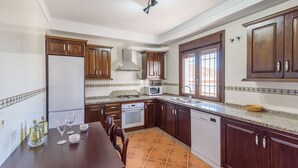 Une cuisine avec des meubles de rangement en bois, une cuisinière, un four à micro-ondes et un lave-vaisselle.