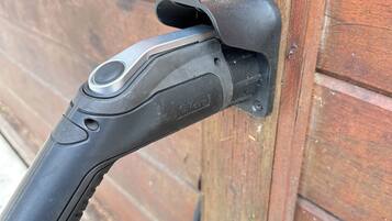 A black object with a circular button and a brand name, attached to a wooden surface.