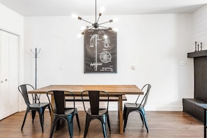 A dining area with a wooden table and four chairs, a wall-mounted light fixture, and a coat rack.