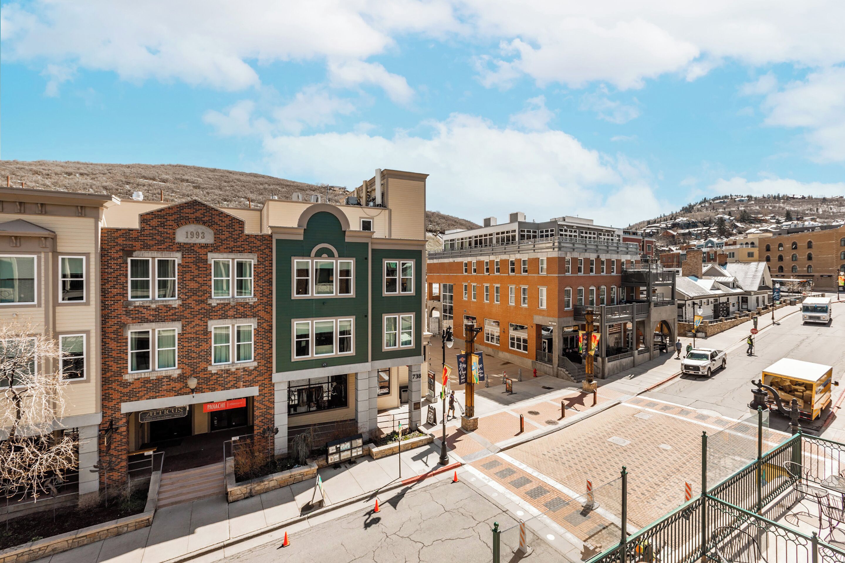 A street view with buildings, a crosswalk, and a hill in the background.