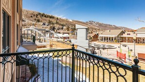 A hotel with a balcony, a ski lift, and a mountainous backdrop.