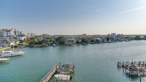 Un puerto deportivo con barcos amarrados, cielo despejado y paisaje urbano al fondo.