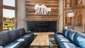 Un salon moderne avec une cheminée, deux canapés en cuir et une table basse en bois.