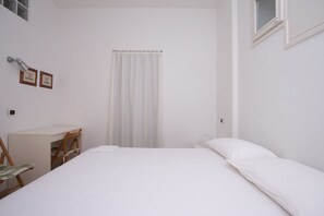 Un dormitorio con cama, escritorio y silla.