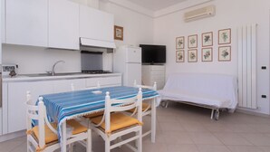 A compact room with a kitchenette, a dining table with chairs, a bed, and a television. - N236 Numana, two-room apartment with sea view in the heart of the town (Numana)