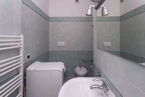 Un baño con inodoro, bidé y lavamanos, todo en blanco.