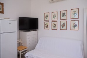 A bedroom with a bed, a TV, a white dresser, a chair, and six framed botanical prints on the wall. - N236 Numana, two-room apartment with sea view in the heart of the town (Numana)