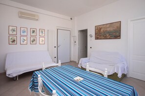 A room with two beds, a striped table, and a painting on the wall. - N236 Numana, two-room apartment with sea view in the heart of the town (Numana)