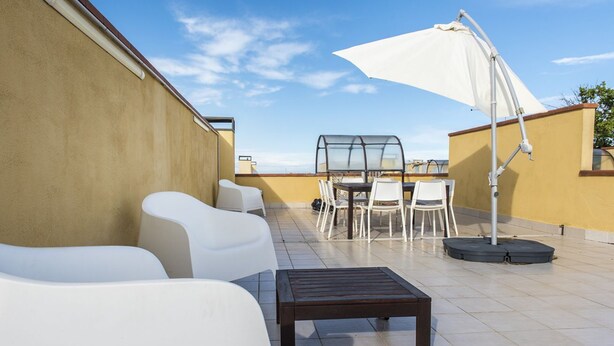 A rooftop terrace with white chairs, a table, and a large umbrella. - M285 - Marcelli, comfortable three-room apartment with terrace (Marcelli)