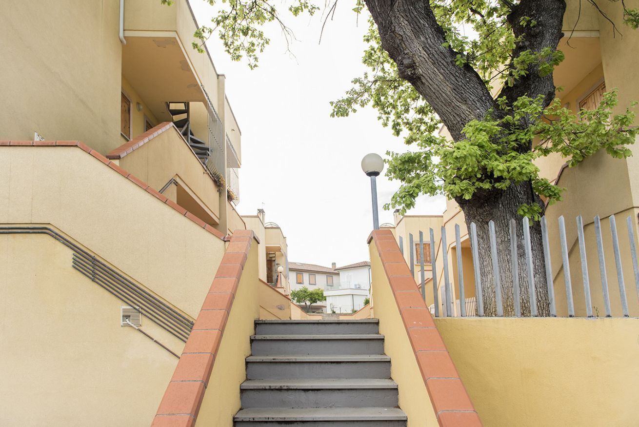 A staircase leading up to a building with a tree on the right.