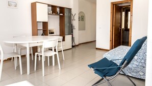 A modern kitchen with white cabinets, a dining table with chairs, and a blue patterned sofa. - M285 - Marcelli, comfortable three-room apartment with terrace (Marcelli)