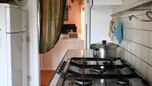 A kitchen with a gas stove, a pot on the burner, and a refrigerator. - M292 - Marcelli, four-room apartment with garden 50 meters from the sea (Marcelli)