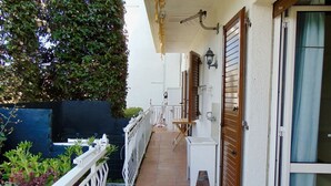 A narrow outdoor corridor with a white railing, a wooden door, and a small table. - M292 - Marcelli, four-room apartment with garden 50 meters from the sea (Marcelli)