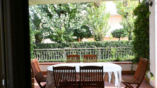 An outdoor patio with a round table and four wooden chairs, surrounded by a white railing and lush greenery. - M292 - Marcelli, four-room apartment with garden 50 meters from the sea (Marcelli)