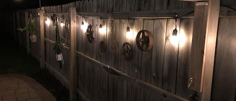 A wooden fence with decorative metal elements and hanging lights.