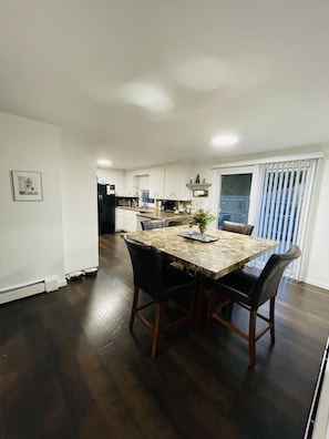A modern kitchen with white cabinets, a marble countertop, and a dining area with a large table and chairs. - 🏈 Minutes from Lambeau • 5 bdrms • Heated Garage • Home Theatre • Game Room (Green Bay)
