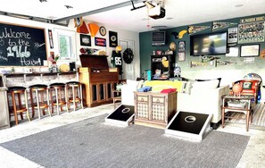 A room with a kitchen area, bar stools, a bed, and a TV.