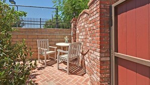 Ein Patio mit Backsteinmauer, rotem Garagentor und einem Drahtzaun.
