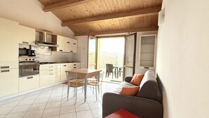 A modern kitchen with a dining area, a sofa, and a view of the outdoors. - N036 - Numana, two-room apartment with terrace in residence with swimming pool (Maratta)