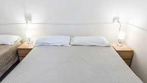 Una habitación de hotel con una cama grande, dos mesitas de noche y dos lámparas de pared.
