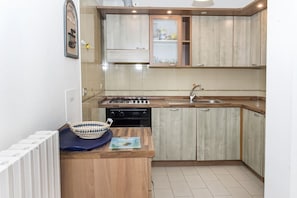 A kitchen with wooden cabinets, a gas stove, a sink, and a small island with a basket.