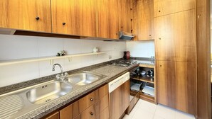 Een keuken met houten kastjes, een granieten aanrechtblad, een roestvrijstalen spoelbak en een vaatwasser.