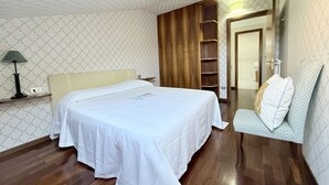 Een slaapkamer met een bed, nachtkastje, lamp, kledingkast en stoel.