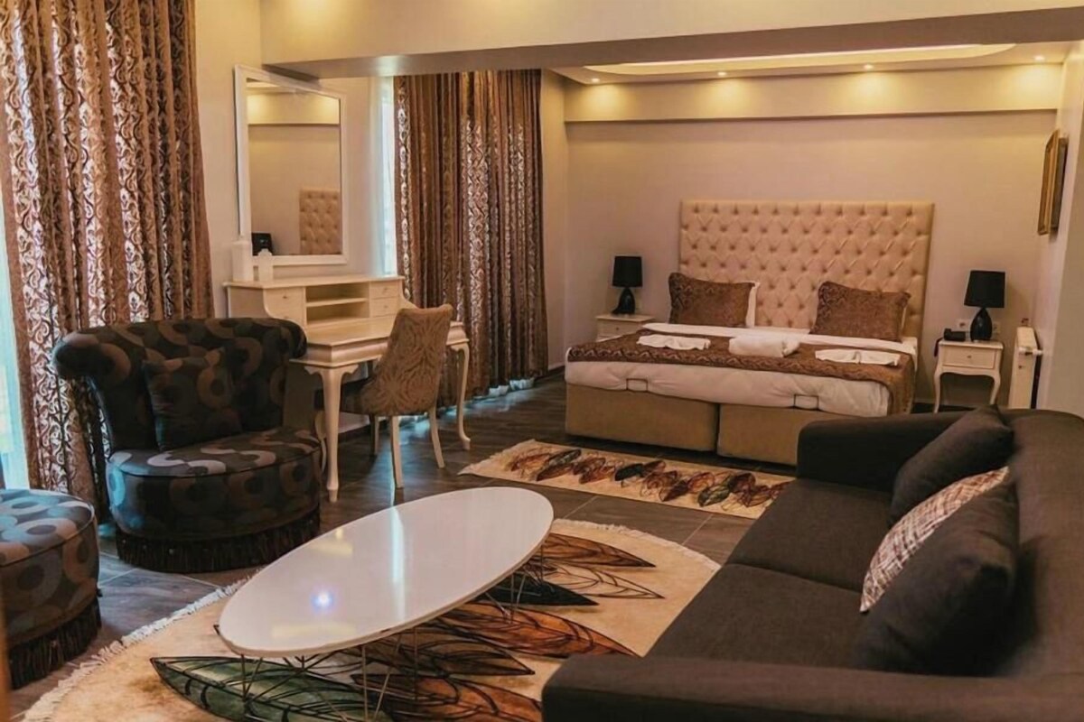 Ein Hotelzimmer mit einem Bett, einer Couch, einem Sessel, einem kleinen Tisch und einem Spiegel.