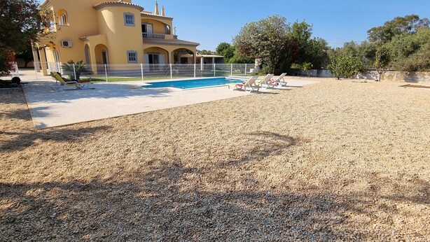 A large building with a swimming pool, surrounded by a gravel area and trees. - 4 bedroom villa with private pool, 5 min from the beach, Wifi included (Moncarapacho)