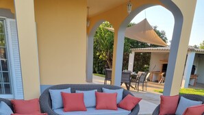 An outdoor seating area with wicker furniture and red cushions, a fire pit, and a well-maintained lawn. - 4 bedroom villa with private pool, 5 min from the beach, Wifi included (Moncarapacho)