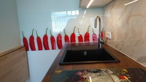 Eine moderne Küche mit einem schwarzen Spülbecken, einer Holzarbeitsplatte und einer Reihe roter Chilischoten an der Wand.